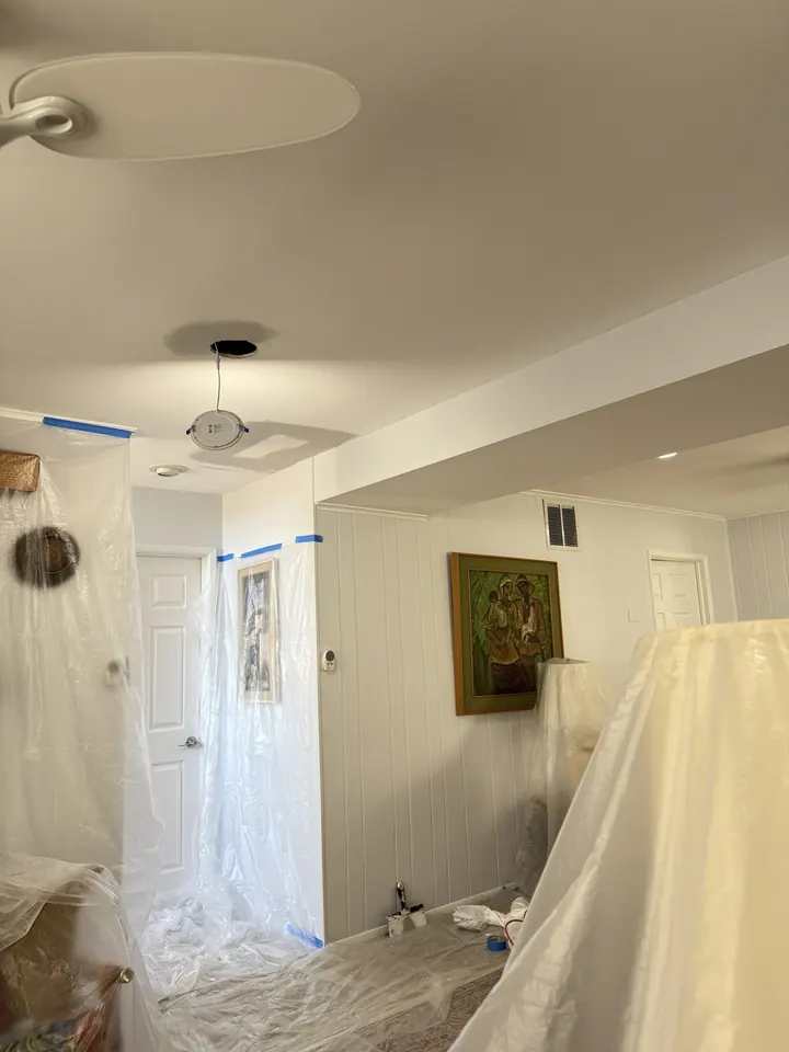 A single opening cut in a ceiling for a light fixture, in a room masked off with protective covering.