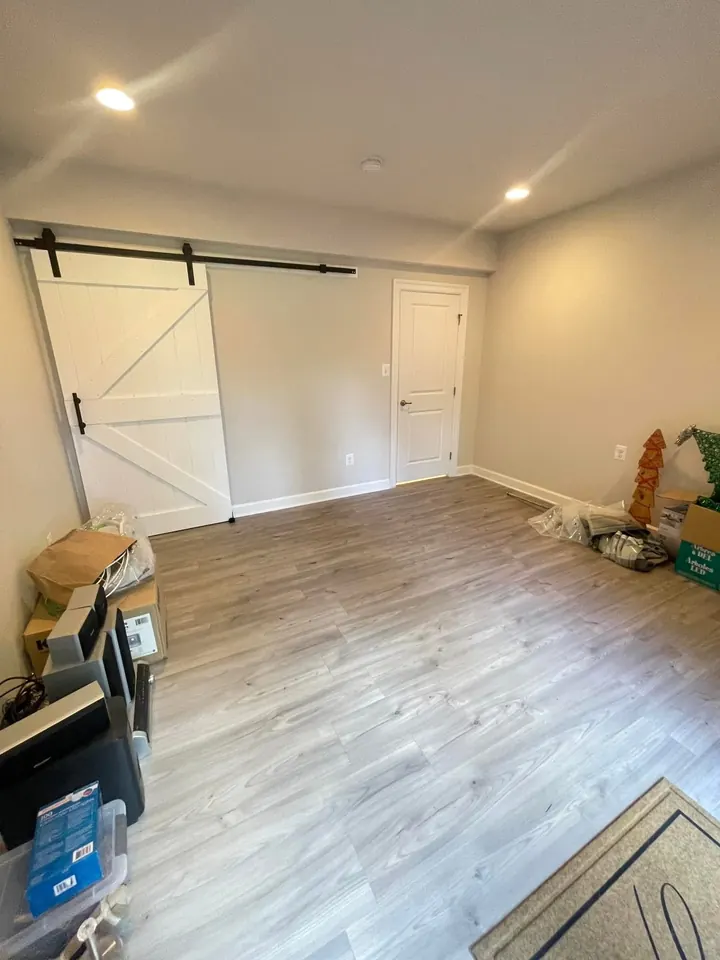 The same basement room after drywall was installed, taped, and finished, with painted walls and a sliding barn door.