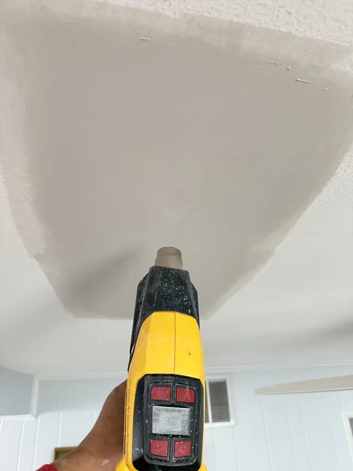 A ceiling being skim coated with joint compound to blend the repair into the surrounding texture.